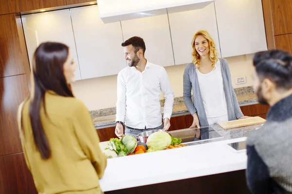 Grupo de hombres y mujeres jóvenes cocinando juntos en casa en la moderna — Foto de Stock