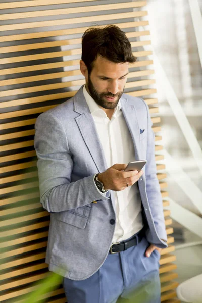 Bonito jovem empresário usando telefone no escritório — Fotografia de Stock