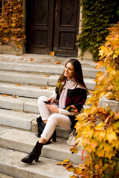 Frau mit Handy im Herbstpark — Stockfoto