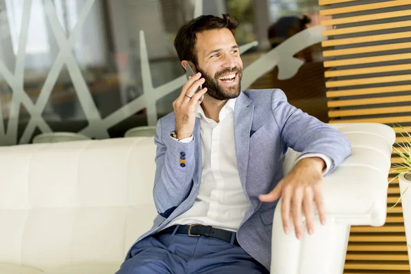 Giovane imprenditore che utilizza il telefono in ufficio — Foto Stock