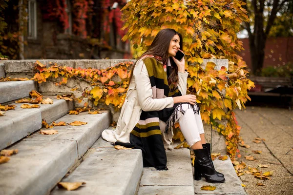 Frau mit Handy im Herbstpark — Stockfoto