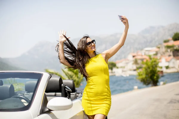 Mujer joven bonita por cabriolet blanco — Foto de Stock