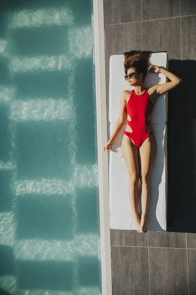 Młoda kobieta, leżąc przy basenie — Zdjęcie stockowe