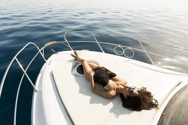 Jovem mulher atraente posa em iate de luxo flutuando no mar — Fotografia de Stock
