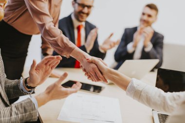 Business people shaking hands finishing up a meeting in office clipart