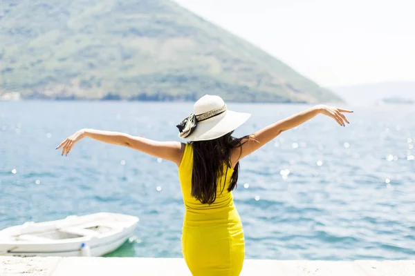 Молода приваблива жінка з капелюшними пози на морі — стокове фото