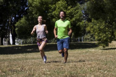 Genç çift parkta koşuyor. 