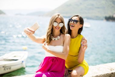 İki genç ve güzel kadın selfie deniz kenarında alarak