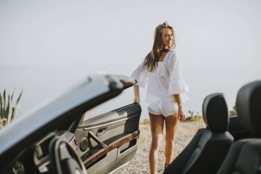 Seaside adlı bir cabriolet yanındaki genç çekici kadın pozlar