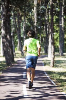 Genç adam parkta koşuyor.