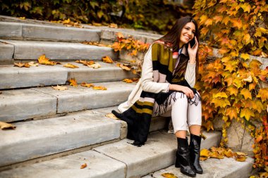 Sonbahar park içinde hareket eden telefon ile genç ve güzel kadın