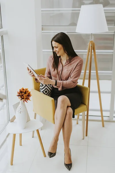 Jeune femme d'affaires assise sur une chaise et tenant une tablette — Photo