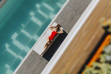 Havuz başında şezlong üzerinde yatan genç kadın