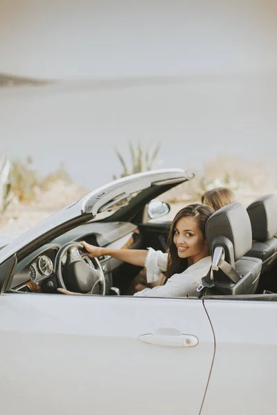 Två glada vänner i vit cabriolet bil som kör överallt — Stockfoto
