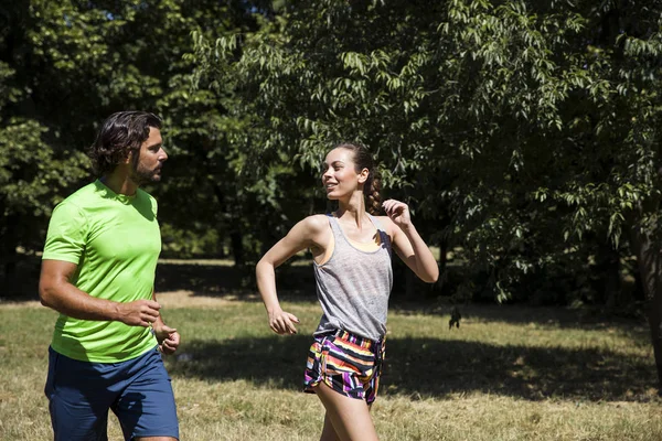 Giovane coppia che corre nel parco in una giornata di sole — Foto Stock