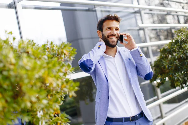 Handsome businessman using mobile phone in front of office build