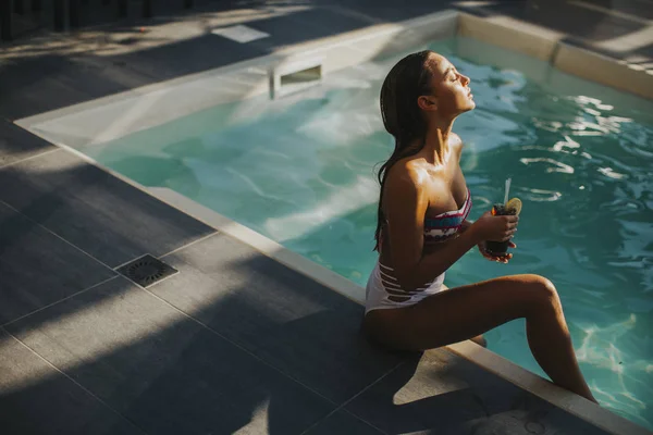 Mujer joven junto a la piscina con cóctel Fotos de stock