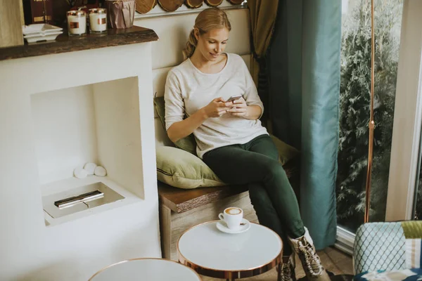 Jeune femme assise dans un café et utilisant un téléphone portable — Photo