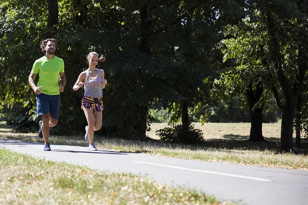 Pareja joven corriendo en el parque en un día soleado —  Fotos de Stock