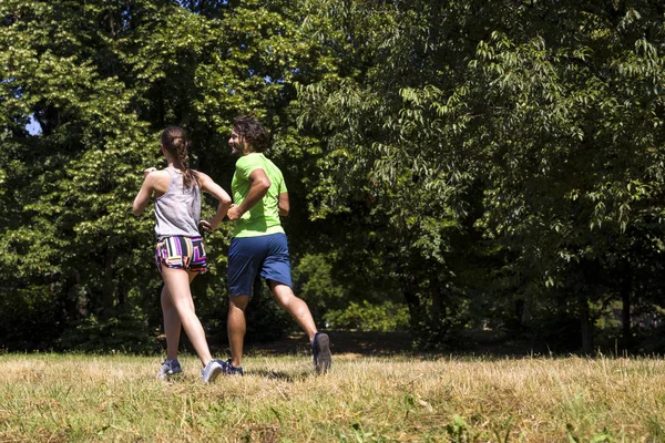 Mladý pár běží v parku za slunečného dne — Stock fotografie
