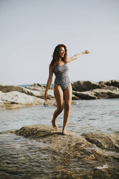 Pretty young woman on the stony shore — Stock Photo, Image