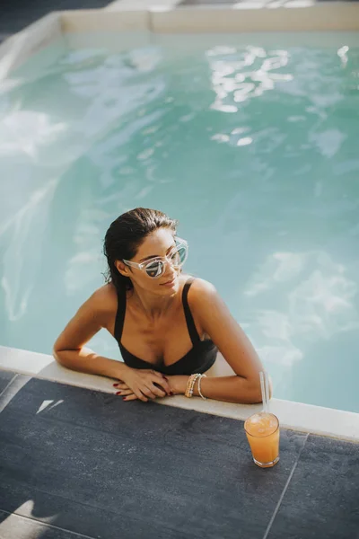 Jonge vrouw aan het zwembad met coctail — Stockfoto