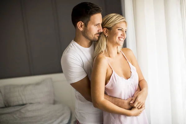 Härlig ung par stående genom fönstret på morgonen — Stockfoto