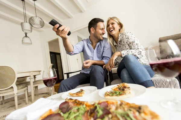 Jovem casal gostando de comer pizza e assistir tv — Fotografia de Stock