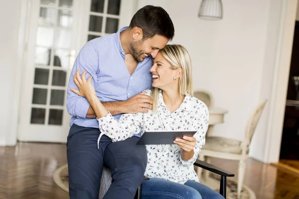 Jovem casal feliz navegando na web em tablet digital em casa — Fotografia de Stock