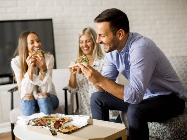Arkadaşlar evde pizza yiyorlar.