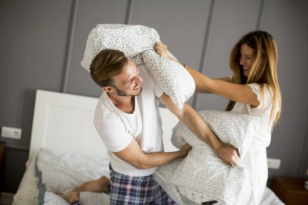 Juguetona joven pareja teniendo almohada lucha en la cama — Foto de Stock