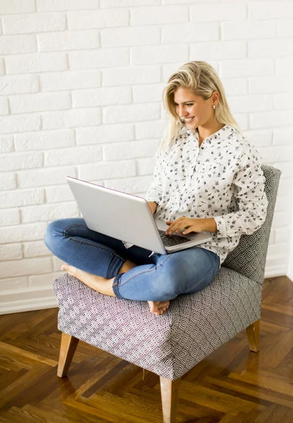 Jeune femme assise sur la chaise et utilise un ordinateur portable — Photo