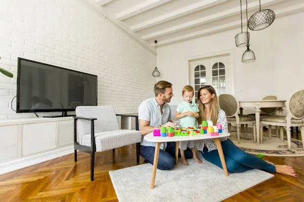 Menino brincando de brinquedos com mãe e pai em casa — Fotografia de Stock