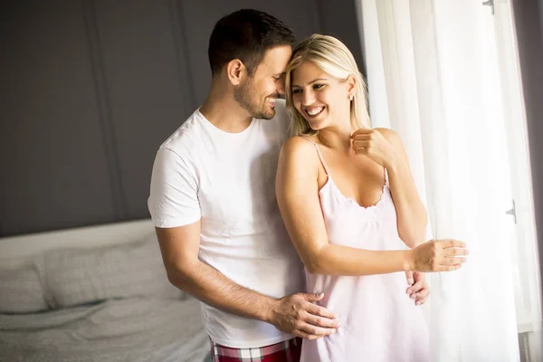 Mooie jonge paar staan bij het raam op de ochtend — Stockfoto