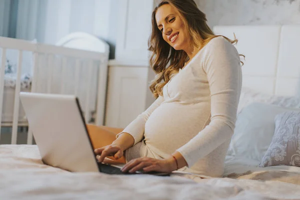 Pregnant woman with laptop on bed — Stock Photo, Image