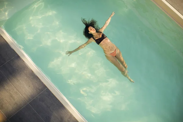 Femme en bikini flottant sur l'eau dans la piscine — Photo