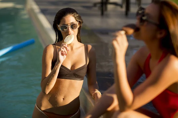 Unga kvinnor äter glass vid poolen — Stockfoto