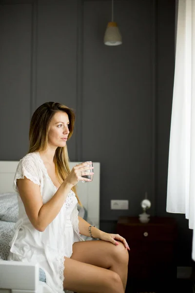 Mulher bebe um copo de água de manhã depois de acordar — Fotografia de Stock