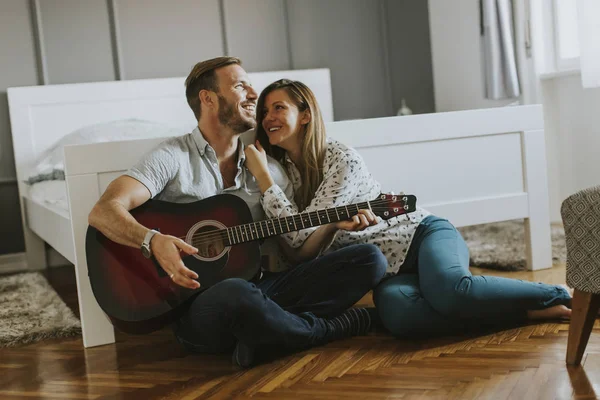 Romantikus pár gitározik a padlón — Stock Fotó