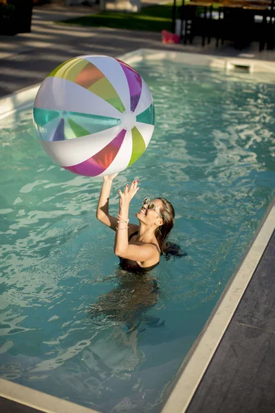Jovens mulheres brincando com uma bola na piscina — Fotografia de Stock