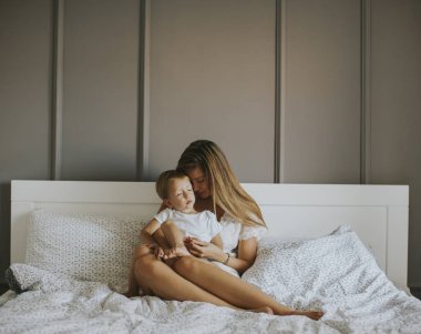 Yatağa küçük çocuk ile oynarken annesi