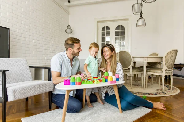 Menino brincando de brinquedos com mãe e pai em casa — Fotografia de Stock