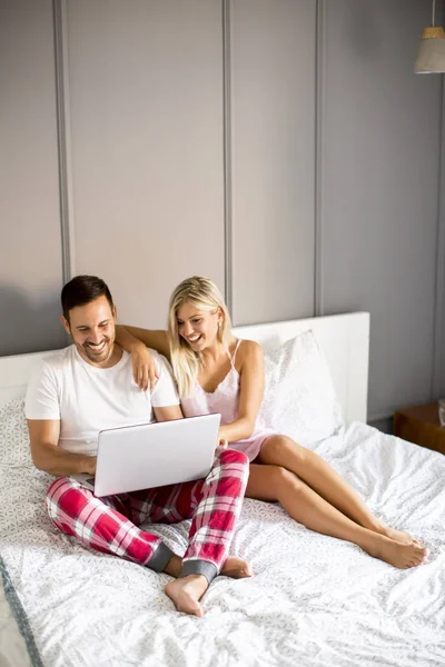 Amantes íntimos usando laptop sentado na cama — Fotografia de Stock