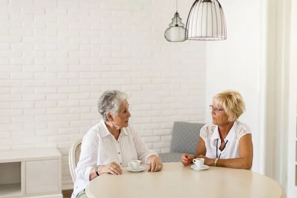 Dos mujeres mayores tomando café en casa y hablando — Foto de Stock