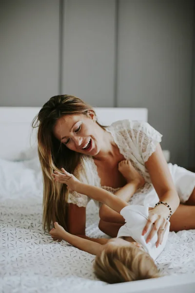 Mother playing with little boy on the bed — Stock Photo, Image