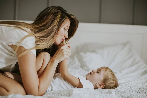 Mamma leker med liten pojke på säng — Stockfoto