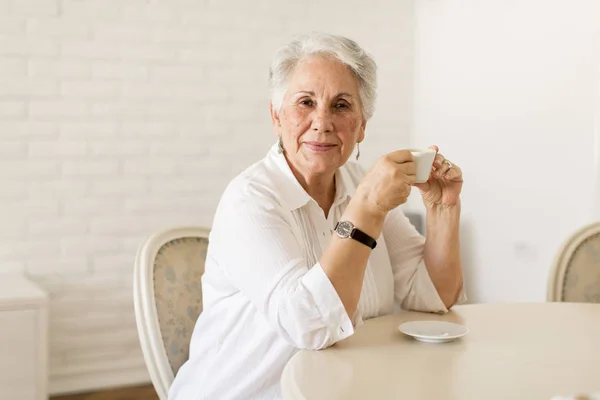 Очаровательная пожилая леди пьет кофе дома — стоковое фото
