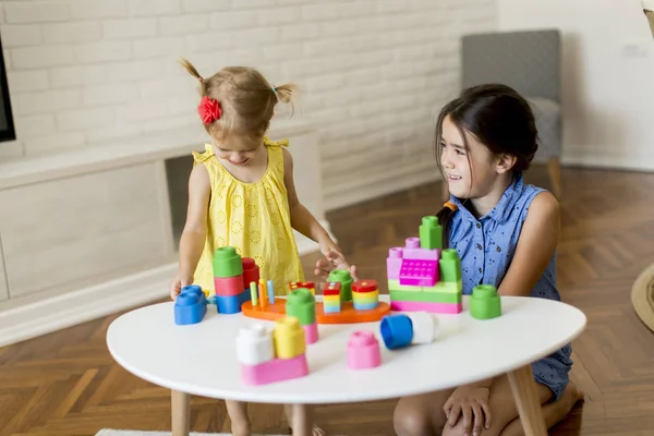 Odada oyuncaklarla oynayan iki küçük kız.