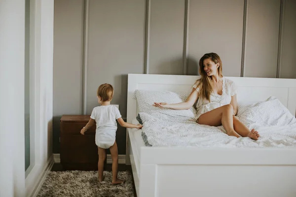 Mamma leker med liten pojke på sängen — Stockfoto