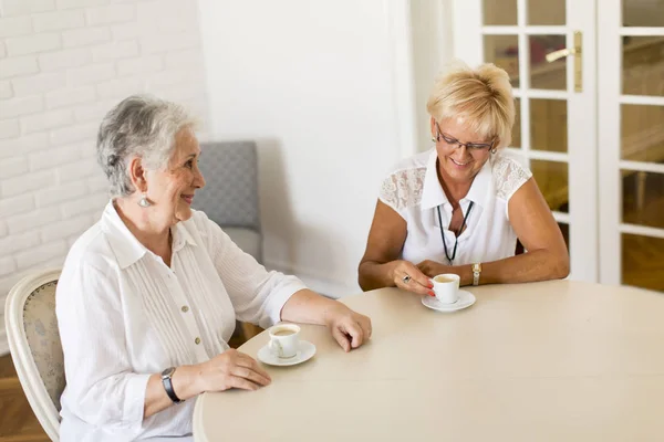 Две пожилые женщины пьют кофе дома и разговаривают — стоковое фото
